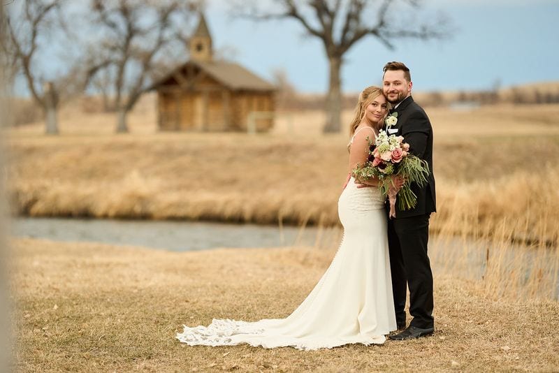 Carlee and Tayven by the pond, the little chapel behind them