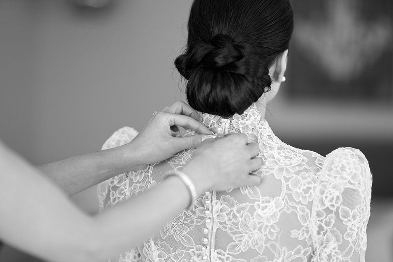 Her mother fastening the last buttons of the dress
