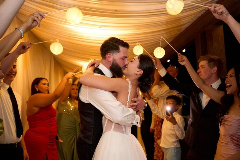 A kiss under the lanterns as the guests send them off