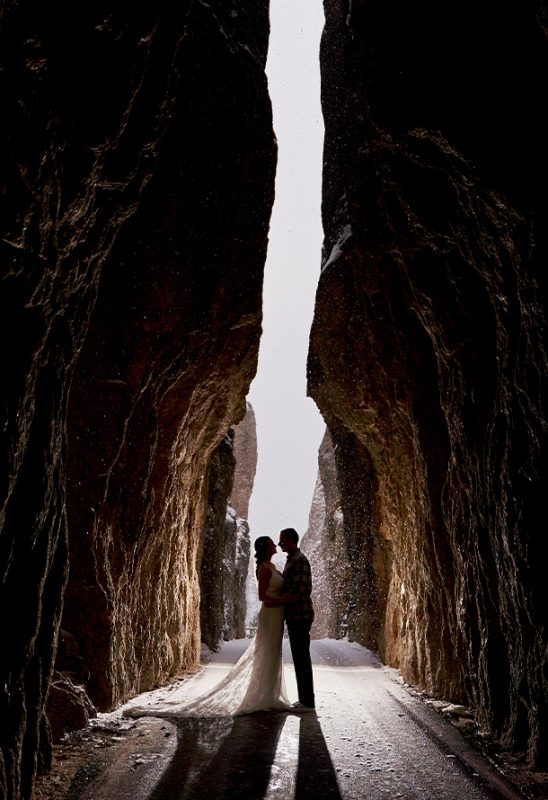 A couple kissing in a rock tunnel on Needles Highway, with snow falling