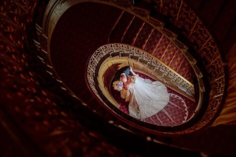 wedding couple kissing at bottom of red spiral staircase