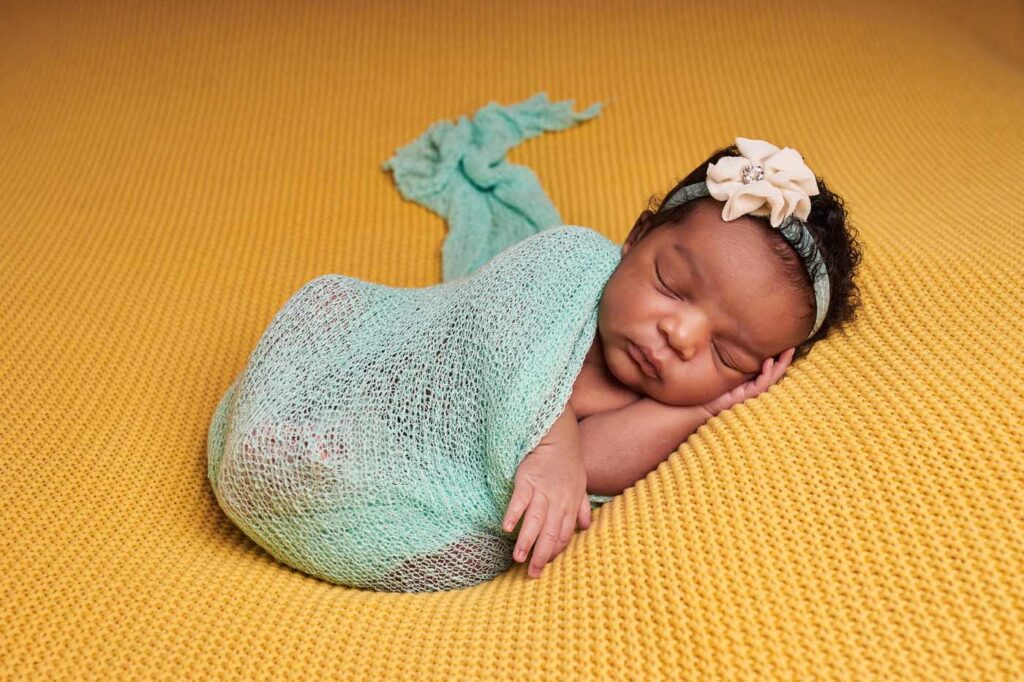 newborn baby girl wrapped in mint on a golden background, rapid city newborn photographer