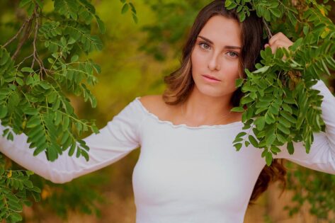 Senior high school girl leaning into green branches, rapid city senior photographer