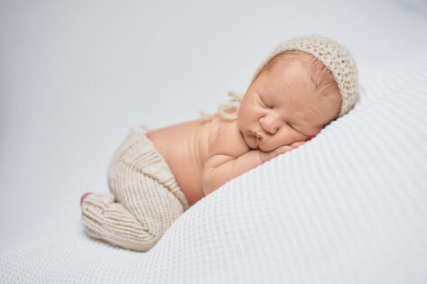 newborn baby boy sleeping on a white blanket