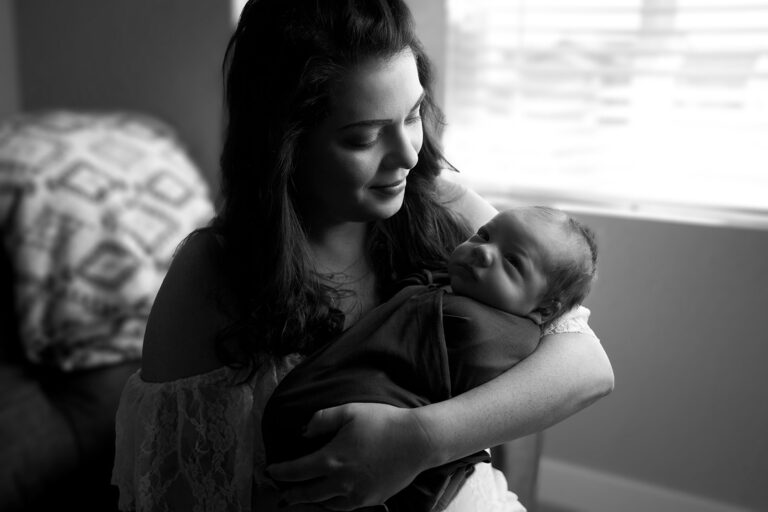 mom looking at newborn baby boy in her arms, rapid city newborn photographer
